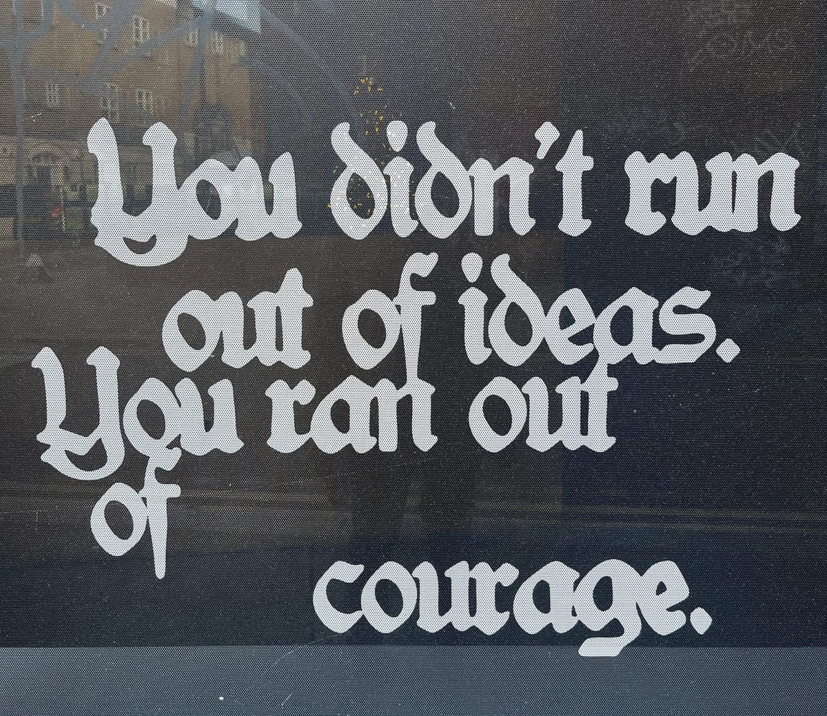 a shopfront window with the words “You didn’t run out of ideas. You ran out of courage.”